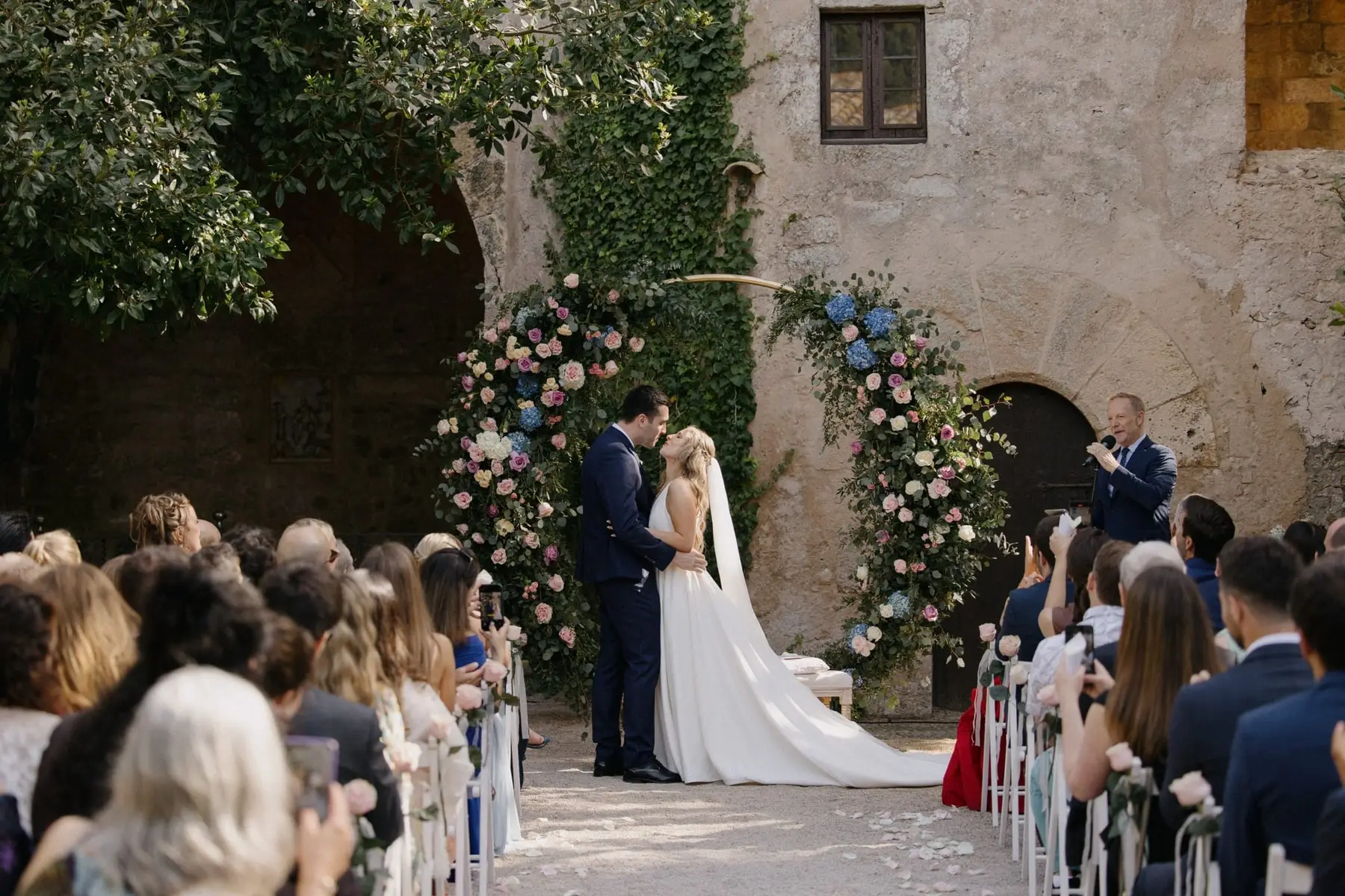 The couple beneath a great floral arch in the courtyard