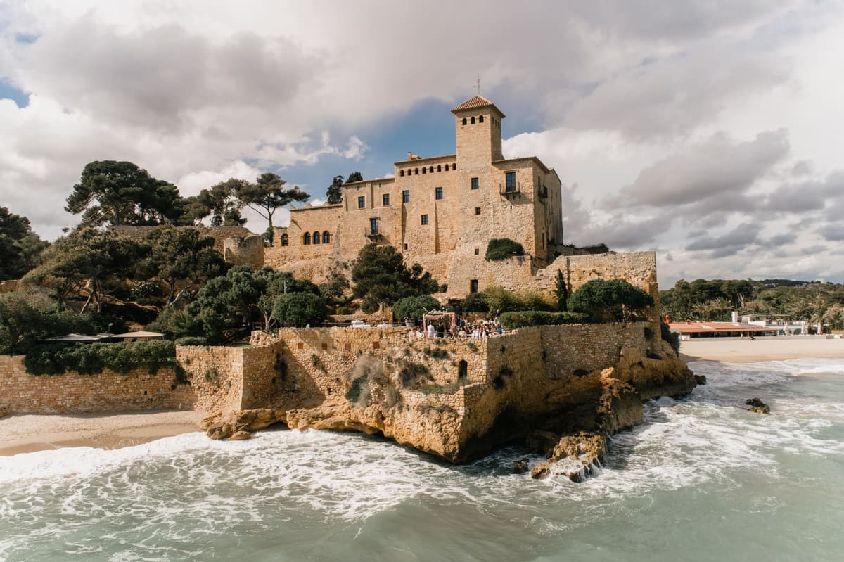 Tamarit Castle on its rock, with surf at its feet beneath a sky of clouds