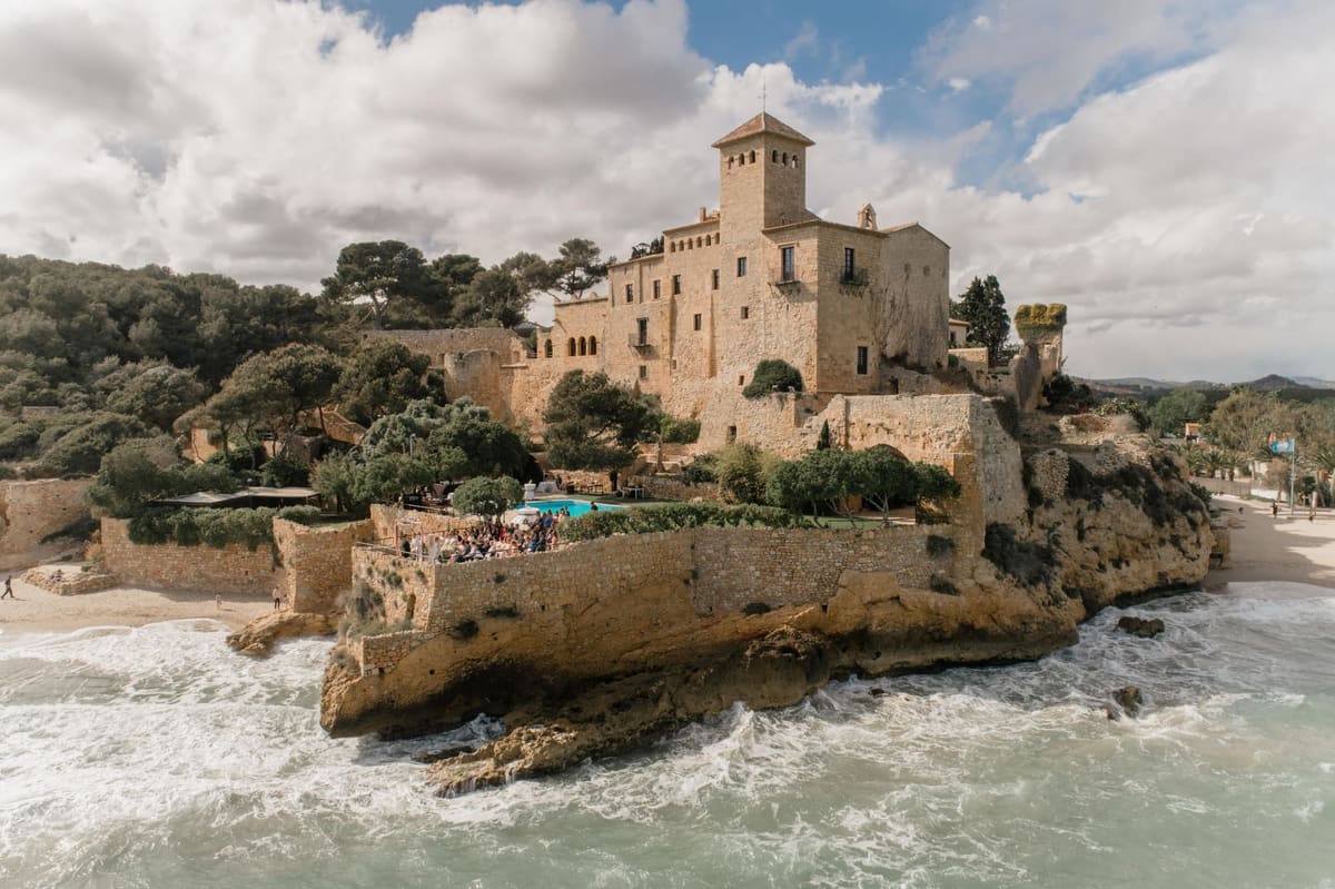 The castle on its rock above the surf, with guests on the terrace by the pool